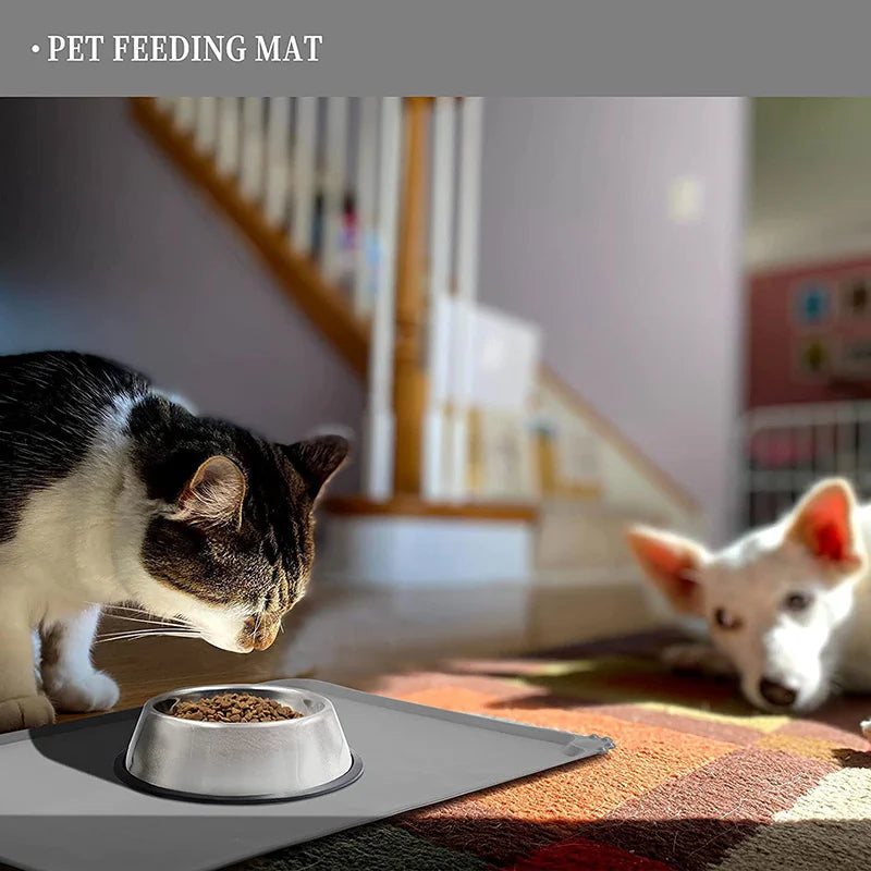 Silicone Pet Food Mat under a pet bowl with a cat eating and a dog in the background on a colorful rug.
